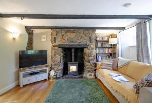 a living room with a stone fireplace and a couch at Berry Cottage in Croyde