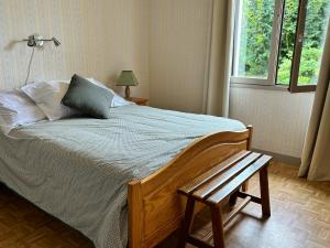 a bedroom with a bed with a bench and a window at Chez Colette, maison agréable in Villebernier