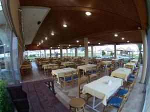 an empty restaurant with white tables and chairs at Hotel Akrogiali in Korinos