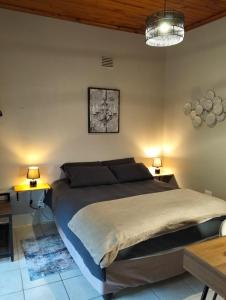a bedroom with a large bed and two lamps at Charming Cottage in Prime Location in Gqeberha