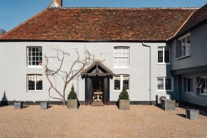 ein weißes Gebäude mit einer Tür und einem Baum in der Unterkunft The Alfriston in Alfriston