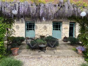 a stone house with purple wisteria hanging over a patio at Hungry Grape Guests in Erdőbénye