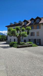 Appartement atypique au cœur de Sallanches في سالونش: مبنى ابيض كبير امامه شجرة