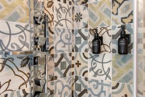a bathroom with a tile wall with two bottles on it at La chambre d'Emilie - romantic room in Valtournenche