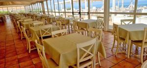 eine Reihe von Tischen und Stühlen in einem Restaurant in der Unterkunft Futura Style Acqua di Mare Resort in Marina di Sorso + 15 Fotos