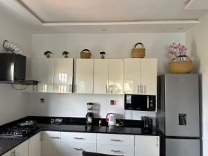 a kitchen with white cabinets and a black counter top at Maison blanche in Porto-Novo