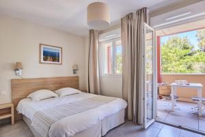 a bedroom with a bed and a large window at Odalys Résidence et Spa Les Canissons in Cavalaire-sur-Mer +90 photos