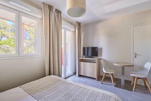 a bedroom with a bed and a table and two chairs at Odalys Résidence et Spa Les Canissons in Cavalaire-sur-Mer