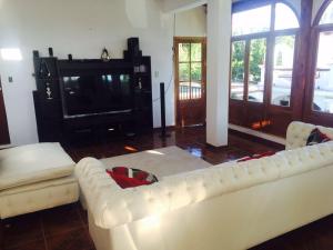 a living room with a white couch and a television at Hostal Andino - Adults Only in Cafayate