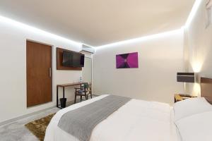 a white bedroom with a bed and a desk at Hotel Urban 101 in Chetumal