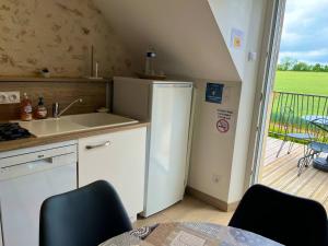 a kitchen with a refrigerator and a table and a balcony at La Suite Etoilée - Balnéo privative in Courgains