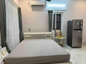 a small bedroom with a bed and a refrigerator at Woodside Haven Luxury GF in Auroville