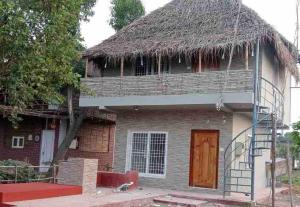 a house with a thatched roof and a staircase at Woodside Haven Luxury GF in Auroville