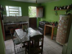 une cuisine avec une table et une cuisine avec des murs verts dans l'établissement Casa na Vila, à Vale do Capão