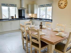 eine Küche mit einem Holztisch mit Stühlen und einer Uhr in der Unterkunft Salar's Rest - 28028 in Alnmouth