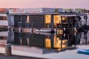a boat sitting on the water in front of a building at Hausboot EL-SOL in Braunsbedra