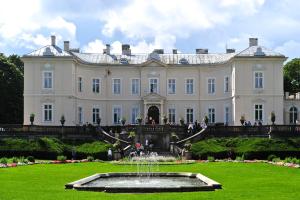 a large white house with a fountain in the yard at Adelės Vila in Palanga