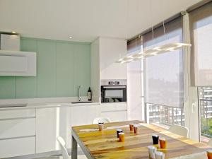 cocina con mesa de madera y armarios blancos en Ferran Pedralbes Penthouse, en Barcelona