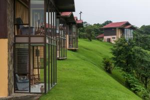 a house on a hill with a grassy yard at Hotel Arenal Lodge in Fortuna