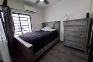 a bedroom with a bed and a window and a dresser at La Casita in Puerto Peñasco