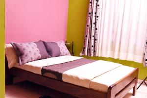 a bedroom with a bed with purple and green walls at Carmella Exquisite Home Jjanda in Natonko