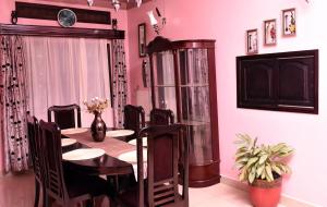 a dining room with a table and chairs and pink walls at Carmella Exquisite Home Jjanda in Natonko