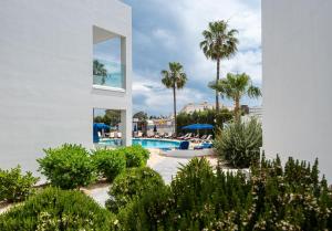 a white building with a swimming pool and palm trees at Bellini Hotel in Ayia Napa