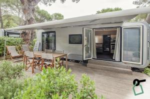 an rv with a wooden deck with a table and chairs at HOTIDAY Lodge Castiglione in Castiglione della Pescaia