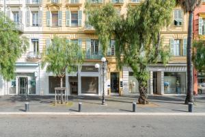 une rue avec des arbres devant un bâtiment dans l'établissement Nice Renting - VERDUN - Designer Cocoon Massena Calm Air Conditioning, à Nice