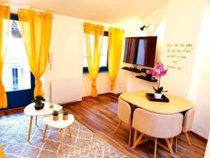 a living room with yellow curtains and a table and chairs at 1 Liberte - TRIPLEX in Saint-Affrique