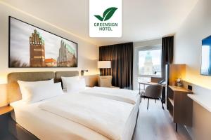 a hotel room with a large bed and a desk at Welcome Hotel Darmstadt City Center in Darmstadt