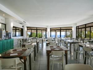a restaurant with tables and chairs and windows at Hotel MARINELLA parking wi-fi spiaggia attrezzata in Capo Vaticano
