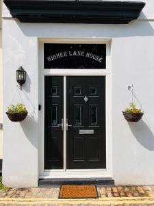 a black front door of a house with two baskets of flowers at Higher Lane House in Plymouth