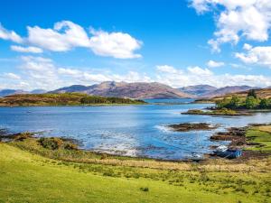 een groot waterlichaam met bergen op de achtergrond bij Brightwater Cottage in Arnisdale