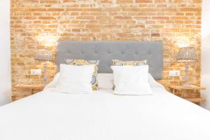 białe łóżko z poduszkami i ceglaną ścianą w obiekcie Alohamundi Ardilla w Sewilli