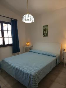 a bedroom with a blue and white bed and a window at Country house La grande quercia in SantʼAntìoco +13 photos