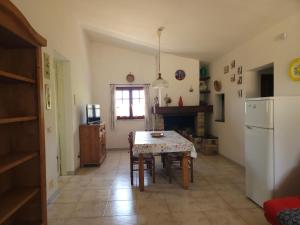 a kitchen with a table and a white refrigerator at Country house La grande quercia in SantʼAntìoco