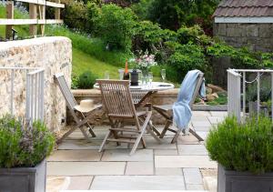 a patio with a table and chairs in a garden at The Old Workshop, Monkton Combe - Elegant Cotswolds Retreat near Bath in Bath