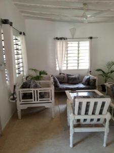 sala de estar con muebles blancos y 2 ventanas en Savanna Breeze Villa, en Malindi