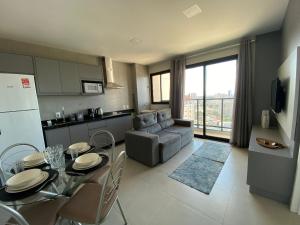 a kitchen and living room with a table and a couch at Apartamento Aconchegante e Completo no Coração da Cidade in Dourados