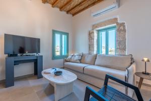 a living room with a couch and a tv at Kimolos Vibes Suites in Kimolos