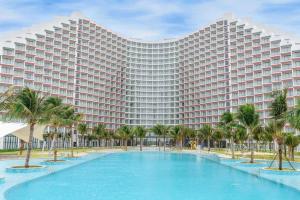 a large hotel with a large swimming pool and palm trees at Arena Resort Cam Ranh in Cam Ranh International Airport