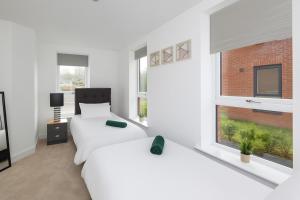 two beds in a white room with a window at Copper Beech by Alt-Stay - 2 Bed En Suite Contractor, Corporate & Relocation Accommodation near LBA with EV Plug, Parking, King Bed, Workspace, Kitchen, Smart TV and Wi Fi - Long Stay Ready with Weekly and Monthly Rates in Horsforth
