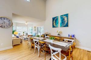 a dining room with a table and chairs and a clock at Bay Dreams --- 31415 Erie Ave in Ocean View