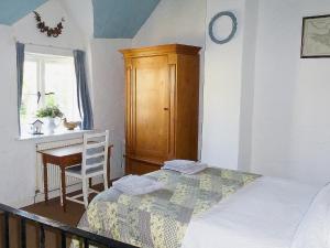 ein Schlafzimmer mit Bett, Schreibtisch und Fenster in der Unterkunft Hollies Cottage in Draycott