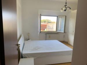 ein Schlafzimmer mit einem weißen Bett und einem Fenster in der Unterkunft Marechiaro in Anzio