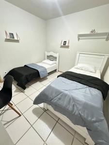 a bedroom with two beds and a chair in it at J Lindo Sobrado 2 quartos em condomínio no Centro in Marília