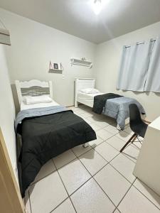 a room with two beds and a chair in it at J Lindo Sobrado 2 quartos em condomínio no Centro in Marília