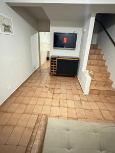a living room with a tv and a staircase at J Lindo Sobrado 2 quartos em condomínio no Centro in Marília