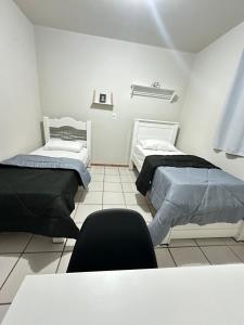 two beds in a room with a table and chairs at J Lindo Sobrado 2 quartos em condomínio no Centro in Marília